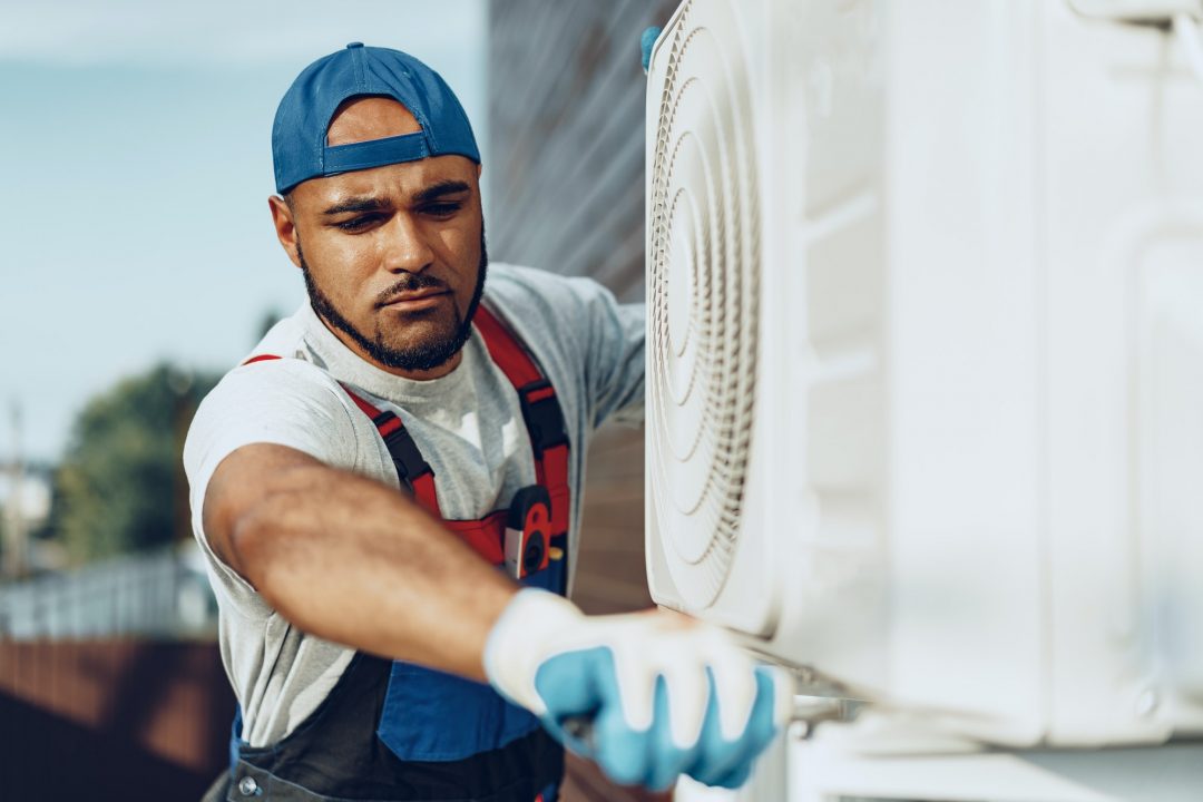 young black man repairman checking an outside air conditioner unit